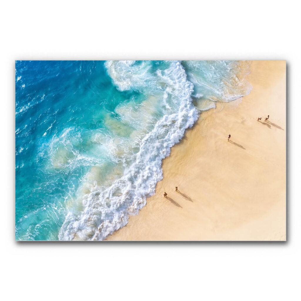 Wandbild mit Raumakustik Strand und Meer aus der Vogelperspektive, türkisblaues Wasser trifft auf hellen Sandstrand mit weißer Brandung, sommerliche Küstenszene, schalldämmendes Wandbild.
