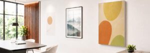 Ansicht eines Raumes mit Tisch und 3 verschiedenen Bildern an der Wand: 1) Poster, 2) Bild im Glasrahmen, 3) Akustikbild.