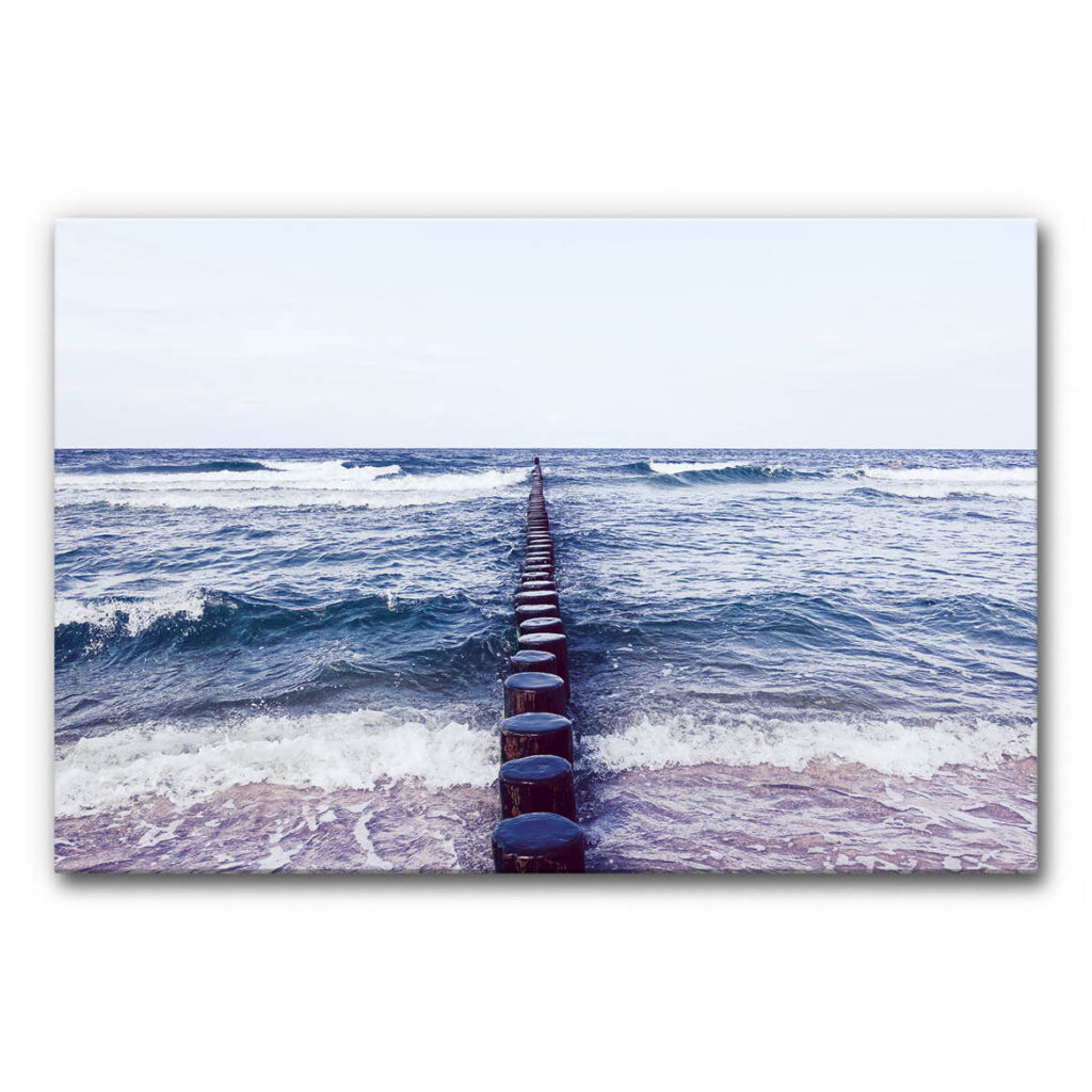 Schallabsorberbild mit Buhnen im Meer, Holzpfähle führen in die Ostsee mit sanften Wellen und klarem Horizont, ruhiges maritimes Akustikbild.