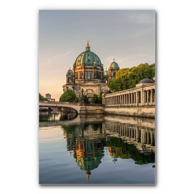 Akustikbild Berliner Dom zeigt den Berliner Dom im warmen Abendlicht, dessen beeindruckende Kuppel sich malerisch im ruhigen Wasser der Spree spiegelt.