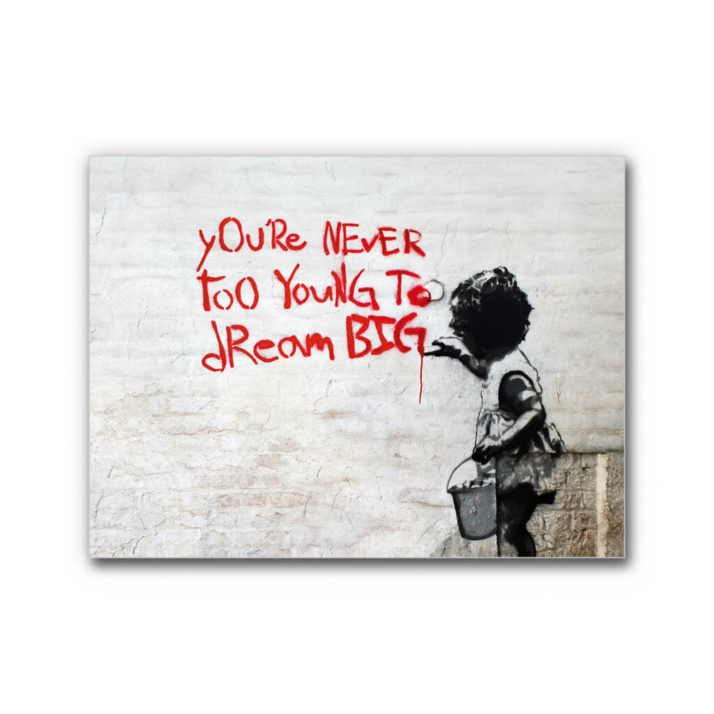 Schallabsorberbild Graffiti Stil mit Kind in Schwarz-Weiß, roter handgemalter Schrift „You’re never too young to dream big“ auf heller Wand im Urban-Art-Look.