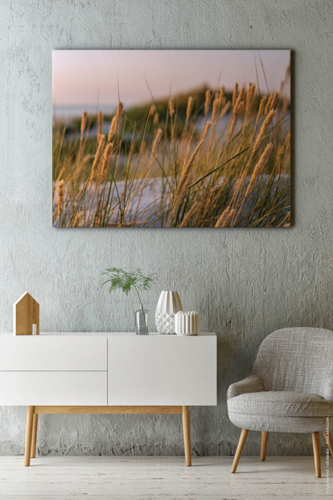 Akustikbilder mit Gräsern in einem Wohnraum mit weißem Sideboard und gemütlichem hellen Sessel